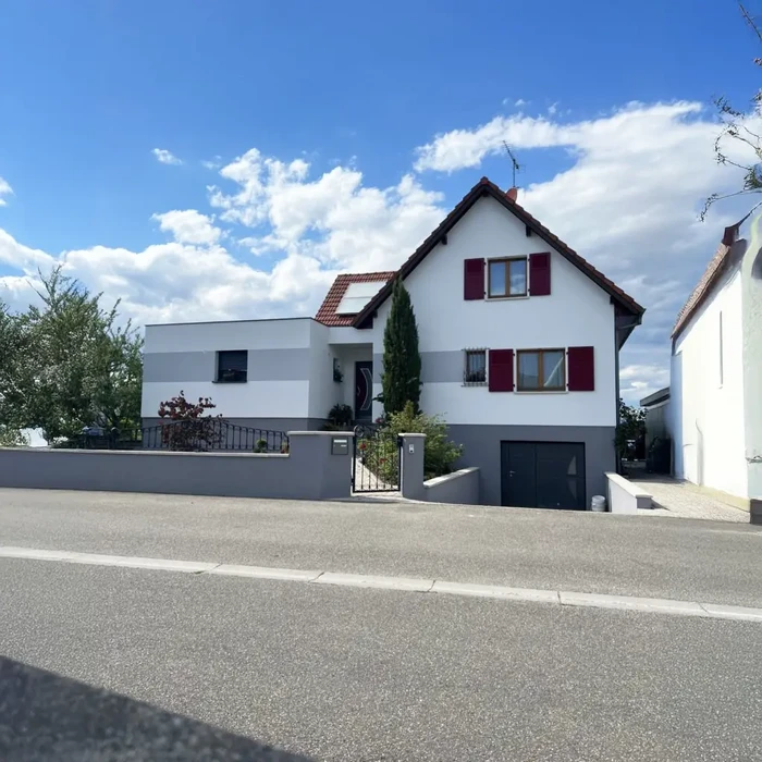Maison individuelle rénovée avec extension moderne, façade blanche et volets rouges, toiture en tuiles terre cuite