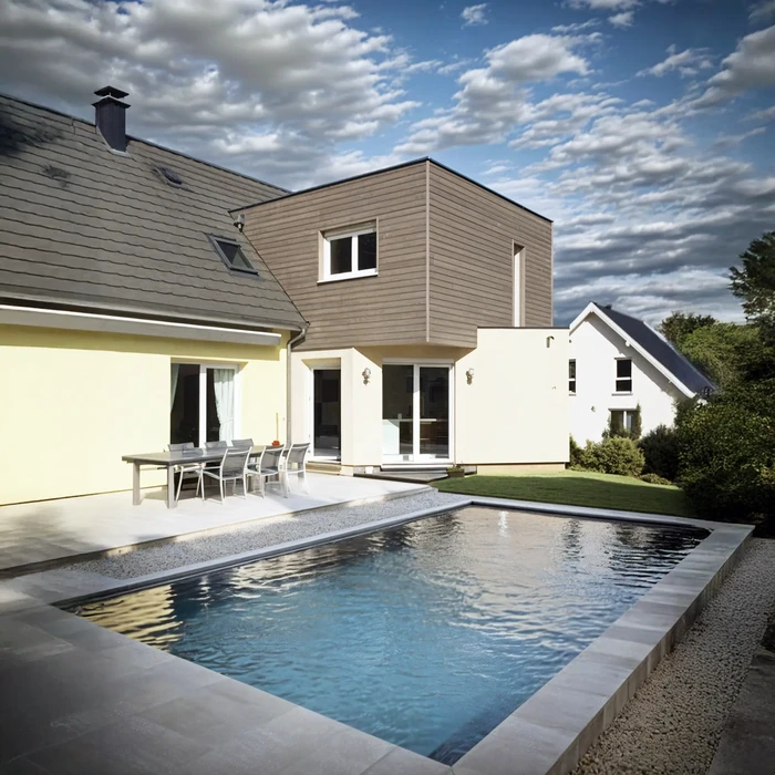 Extérieur résidentiel avec piscine rectangulaire à débordement, terrasse en béton lissé et mobilier de jardin moderne