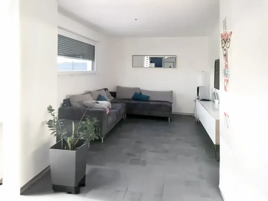 Maison contemporaine avec extension en bardage bois horizontal, terrasse en bois avec mobilier design orange, jardin paysager verdoyant sous ciel bleu